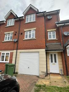 a red brick house with a white garage at Lovely 3-Bedroom Townhouse in Harold Wood