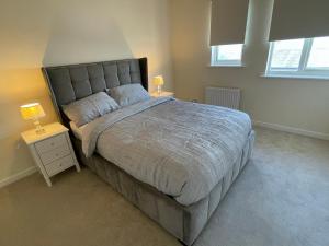 a bedroom with a large bed and two night stands at Lovely 3-Bedroom Townhouse in Harold Wood