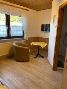 a room with a table and a chair and a television at Pension am Eichenhain in Nuremberg