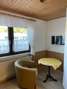 Sala de estar con silla, mesa y TV en Pension am Eichenhain, en Núremberg