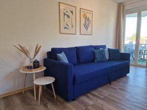 Sofá azul en la sala de estar con mesa en Come4Stay Passau - Wohnung Guby - 2 Zimmer I bis zu 4 Gäste, en Passau