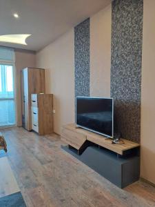 een woonkamer met een flatscreen-tv aan de muur bij Луксозен апартамент с гледка към парк и център in Yambol