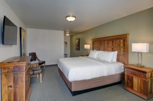 Dormitorio con cama, escritorio y TV en Roosevelt Hotel - Yellowstone, en Gardiner