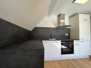 a kitchen with white cabinets and a black wall at Nautilus in Kinheim