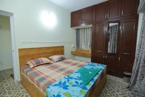 a bedroom with a bed and wooden cabinets at Ritu Homestay in Trivandrum