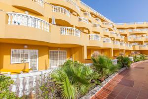 a large yellow building with palm trees in front of it at El Marques Palace by Intercorp Group in Puerto de Santiago