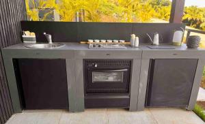 a outdoor kitchen with a fireplace and a sink at Les Hauteurs de Citronnelles in Case-Pilote