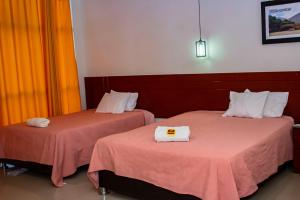 Dos camas en una habitación de hotel con toallas. en La Estancia Hotel, en Huánuco