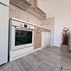 a kitchen with a white oven and wooden cabinets at Apartman "Lola" in Pirot