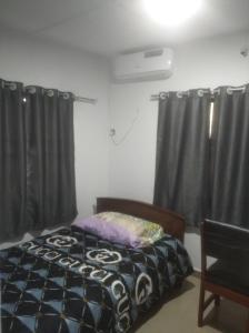 a bedroom with a bed in a room with curtains at chinaka guest house 24hr light in Lagos