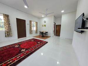 a living room with a red rug and a table at Cantik-La Homestay Kolam 3 Bilik Kuala Terengganu in Bukit Payong