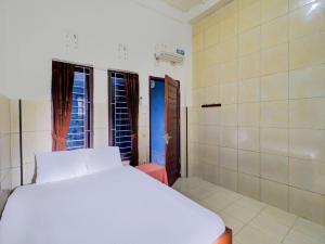 a bedroom with a white bed and two windows at OYO Life 92841 Kos 88 in Negara