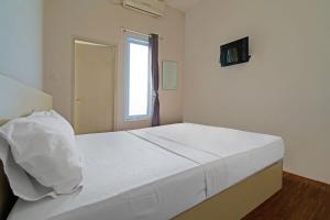 ein weißes Bett in einem Zimmer mit Fenster in der Unterkunft OYO Life 92720 Mekarwangi Guest House in Bandung