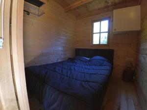 a bed in a log cabin with a window at Les Chalets du Lac Belcaire in Belcaire