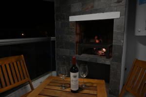 Costa AzulにあるCosta Azul Rent Apartmentsのワイン1本、暖炉付きのテーブルにグラス2杯