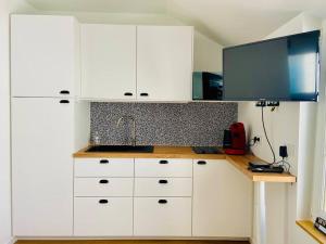 Il comprend une cuisine avec des placards blancs et une télévision murale. dans l'établissement La p'tite Nouba à 300m de la mer, à Cayeux-sur-Mer