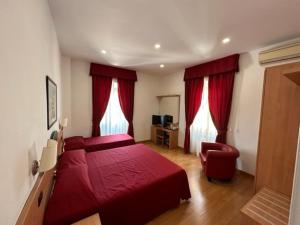 a bedroom with two red beds and a chair at Hotel L'Isola in Santa Marinella