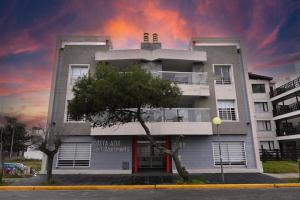 Un edificio blanco con un árbol delante. en Costa Azul Rent Apartments, en Costa Azul