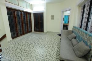 uma sala de estar com um sofá e algumas janelas em Ritu Homestay em Trivandrum