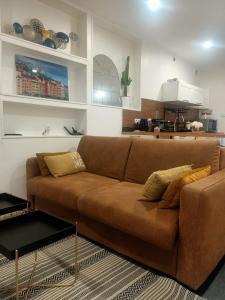 a brown couch in a living room with a kitchen at Le Petit Cocon - Parking privé - Lyon Sud in Vénissieux