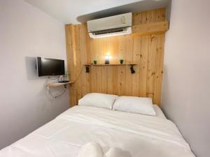 a small bedroom with a white bed and a television at THE BEST ONE CHIANG MAI in Chiang Mai