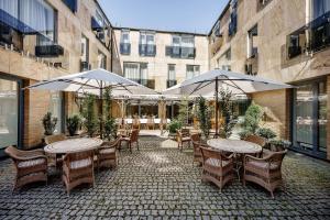 an outdoor patio with tables and chairs and umbrellas at Euterpe Hotel in Klaipėda