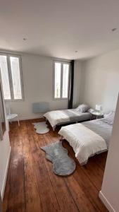 1 dormitorio con 2 camas, suelo de madera y ventanas en Maison entièrement rénovée, en Ambarès-et-Lagrave