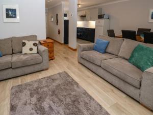 a living room with two couches and a kitchen at Primrose Cottage in Falmouth