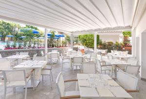 un restaurant avec des tables blanches et des chaises blanches dans l'établissement Family Spa Hotel Le Canne, à Ischia