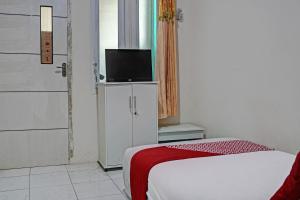 1 dormitorio con 1 cama y TV en un armario en OYO Life 92684 Kost Mutiara Nirwana 