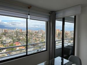 a room with two windows with a view of a city at Depto LAS CONDES-EST ESPAÑOL in Santiago