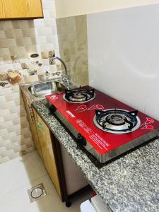 a red stove top in a kitchen next to a sink at Cozy Studio Apartment 2 in Dubai