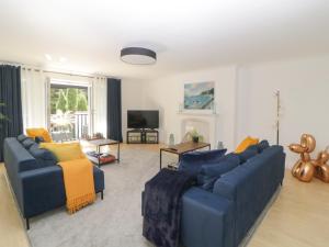 uma sala de estar com dois sofás azuis e uma televisão em Brompton Gardens em Torquay