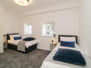 Duas camas num quarto com paredes brancas e almofadas azuis em Brompton Gardens em Torquay