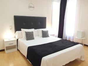 1 dormitorio con 1 cama grande con almohadas blancas y negras en ToledoRooms Palacios, en Toledo