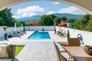 an outdoor patio with a pool and tables and chairs at Villa StellaVita in Lozovac