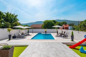 a backyard with a swimming pool and a patio with chairs at Villa StellaVita in Lozovac