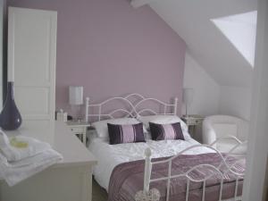 a bedroom with a white bed with purple pillows at Witchingham B&B in Holyhead