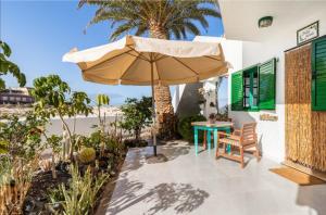 eine Terrasse mit einem Sonnenschirm, einem Tisch und Stühlen in der Unterkunft Apartamento Nire Lula en la misma playa in Cotillo