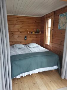 ein Schlafzimmer mit einem Bett in einem Holzzimmer in der Unterkunft Rantahuvila Virranniemi in Vehkataipale