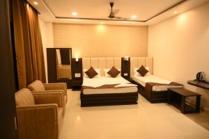 BishnāthHotel Tripti-Biswanath Chariali的一间设有两张床、一张沙发和一把椅子的房间