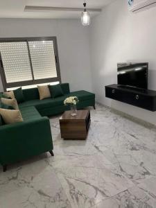 una sala de estar con sofás verdes y un piano en Dar Kmar, en Túnez