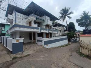 a white house with a palm tree in the background at Ritu Homestay in Trivandrum