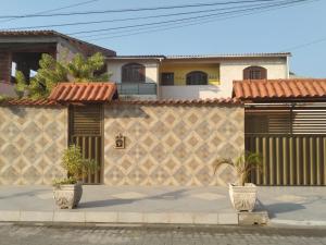 バーハ・デ・サン・ジョアンにあるQuitinetes dos Ipêsの塀の前に二本の植物がある家