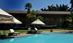 a pool with chairs and umbrellas next to a building at Cresta Lodge Gaborone in Gaborone