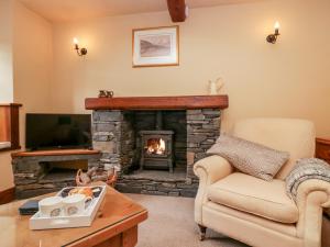 sala de estar con chimenea y sofá en Huntsmans Cottage, en Ulverston