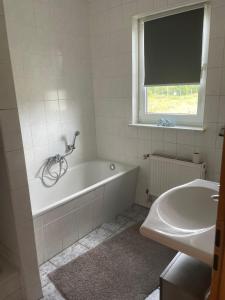 een witte badkamer met een bad en een wastafel bij Wohnung in Möser mit Grillmöglichkeit 