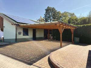 un patio con pérgola de madera frente a una casa en Ferienhaus Am Hang, Carport, alles Barrierefrei, en Blankenburg