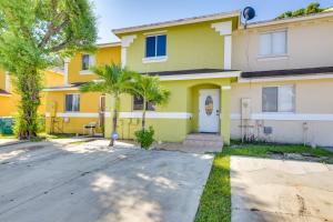 a yellow house with palm trees in front of it at Opa-locka Townhome, 15 Mi to Miami Beach! in Opa-locka