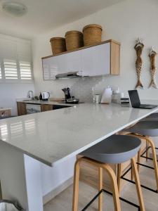 a kitchen with a white counter and stools at KimOcean La Ballito Apartment in Ballito